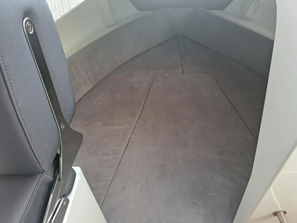 Interior view of a modern boat seating area with grey upholstery and a sleek metal frame, showcasing a spacious layout.